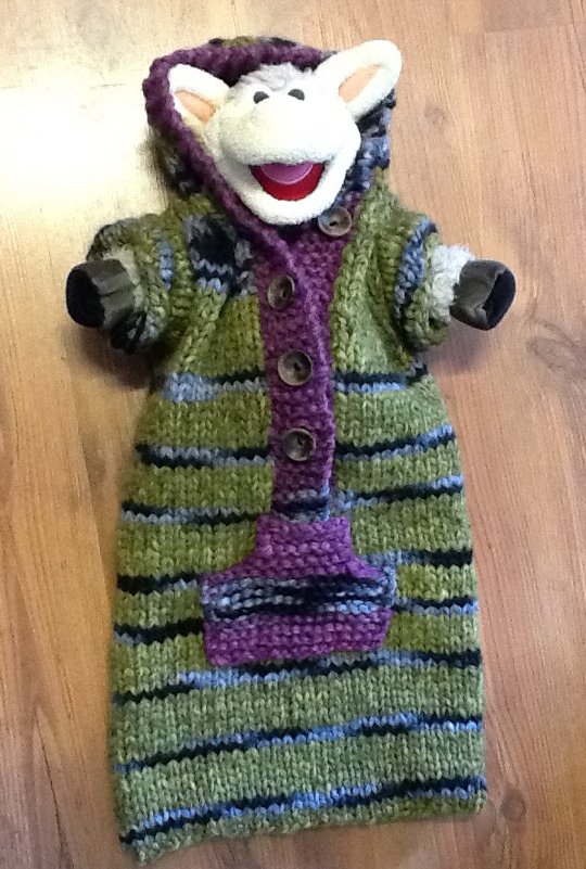 Gestrickter Babyschlafsack mit Kapuze, gestreift in Grün, Lila und Blau; Stofftierkopf schaut hervor