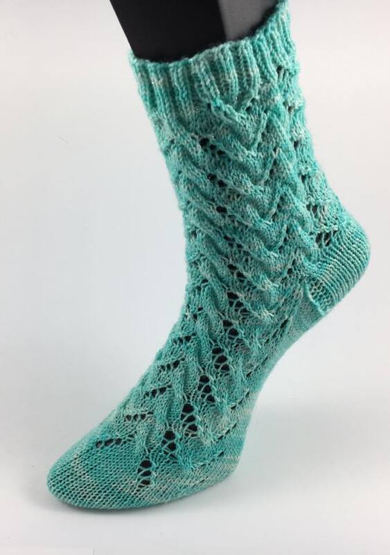Detailansicht einer türkisen gestrickten Damensocke mit Ajourmuster, Bündchen und Ferse