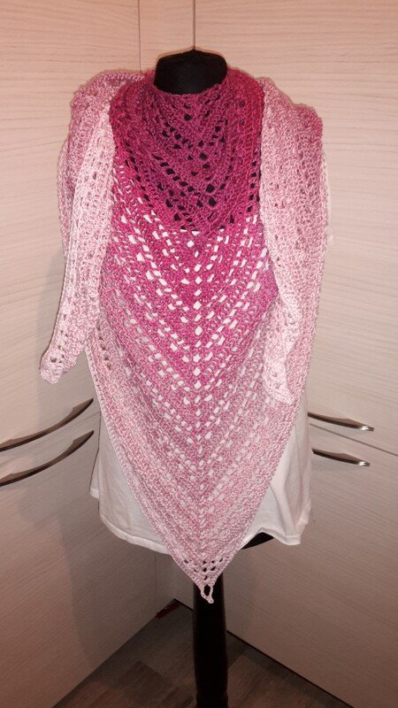 Gehäkeltes Dreieckstuch in Pink- und Rosatönen mit Lochmuster, drapiert auf einer Anziehpuppe.
