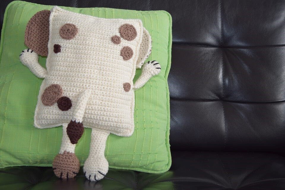 Beige gehäkeltes Hundekissen mit braunen Flecken auf grünem Kissen
