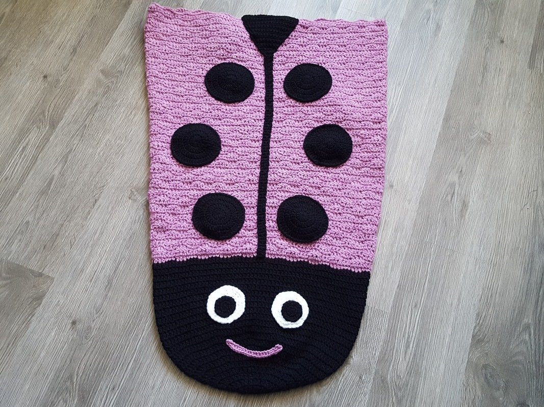 Gehäkelter rosa-schwarzer Babysack im Marienkäfer-Design mit sechs Punkten und Gesicht