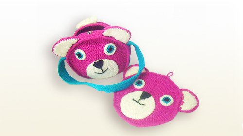 Rosa gehäkelte Bärentasche mit blauem Riemen und ein flacher Bärenkopf als Untersetzer.