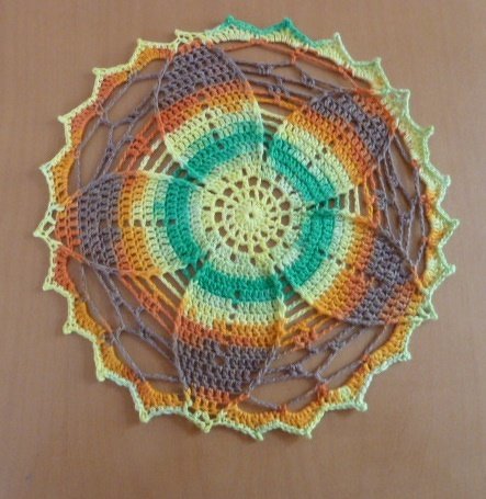 Rundes gehäkeltes Deckchen mit sternförmigem Muster in Gelb, Grün und Orange
