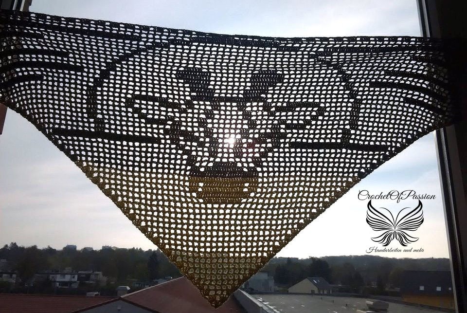 Gehäkeltes dreieckiges Filet-Tuch mit Stierkopf-Motiv vor hellem Fenster