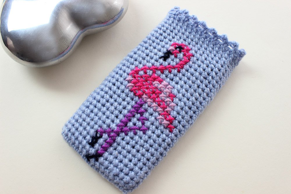 Hellblauer, handgehäkelter Utensilo mit pink-violettem Flamingo-Motiv