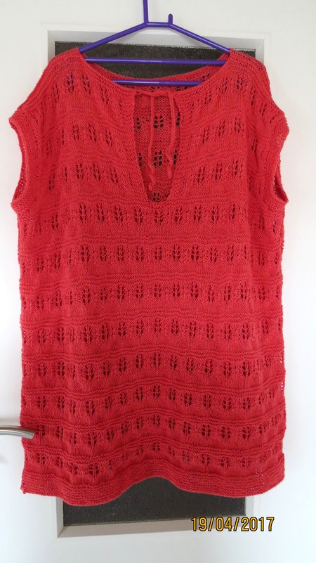 Rotes Stricktop mit Lochmuster und Bindeband am Ausschnitt, aufgehängt an einem Kleiderbügel