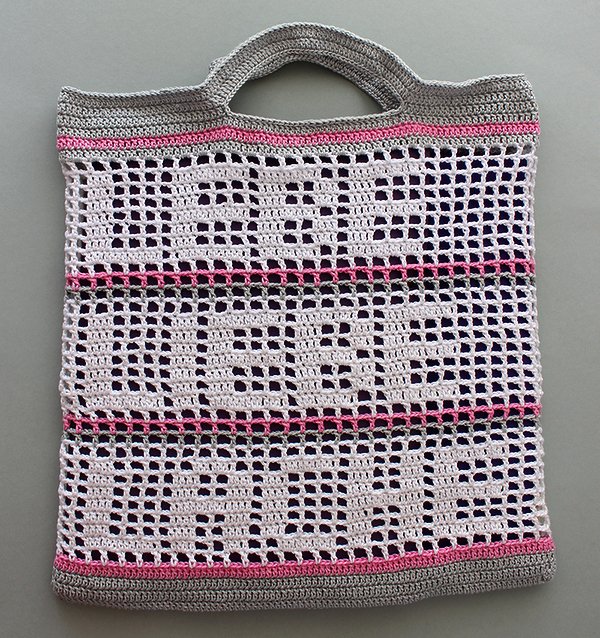 Weiß-grau-rosa gehäkelte Netztasche im Filetmuster mit 'PEACE LOVE PEACE' Schrift