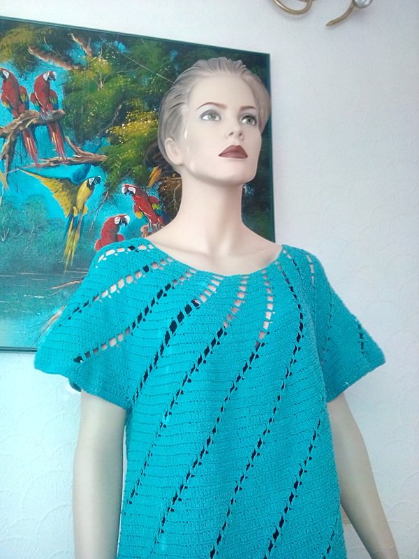 Schaufensterpuppe mit türkisem Häkelshirt, weitem U‑Boot‑Ausschnitt und diagonalem Lochmuster