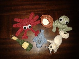 Handgehäkelte Amigurumi-Figuren: Oktopus, Robbe, Delfin, Muschel und Flasche.