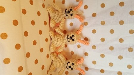 Drei kompakte Amigurumi-Hasen mit Schlaufe, langen Ohren und gestickten Gesichtern