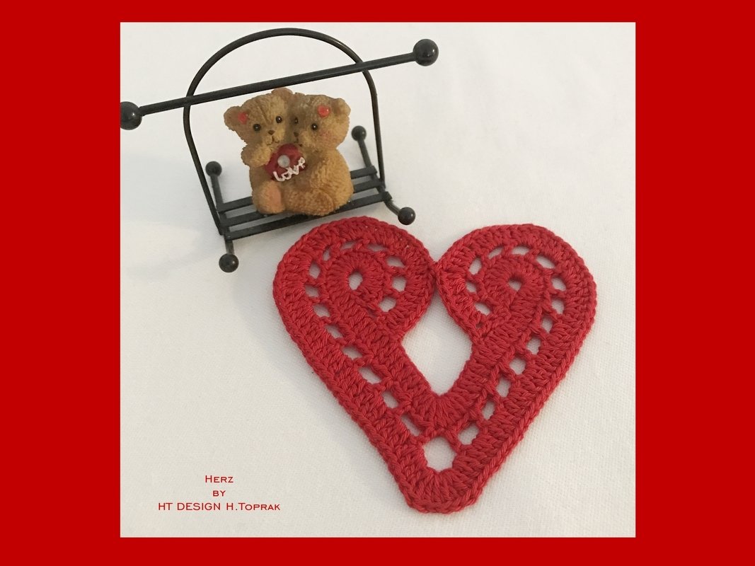 Red crocheted heart appliqué with openwork holes on white background