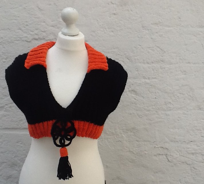 Schwarzer gestrickter Bolero mit orangefarbigem Kragen und Quaste