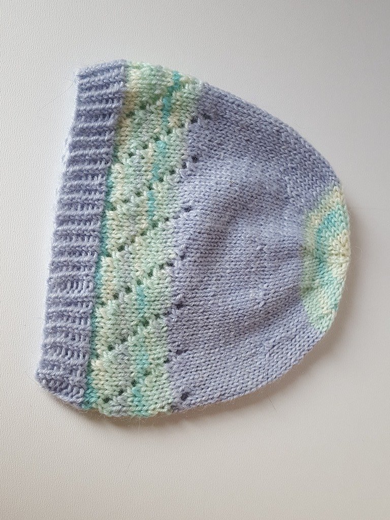 zartlila gestrickte Babymütze mit pastellgrün-meliertem Lochmusterstreifen und geripptem Bündchen