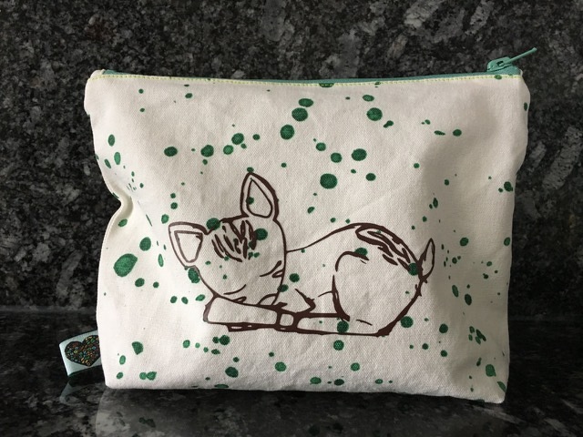 Weiße Stofftasche mit Linienzeichnung eines schlafenden Rehkitzes und grünen Farbsprenkeln