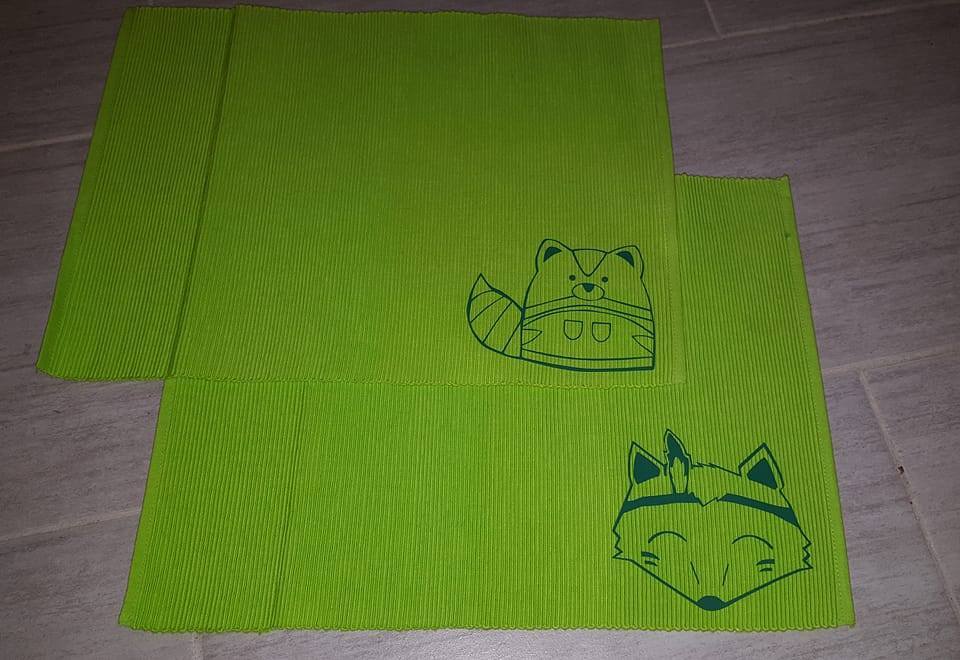 Zwei grüne, gerippte Stoffstücke mit dunklen Umrissmotiven von Fuchs und Waschbär.