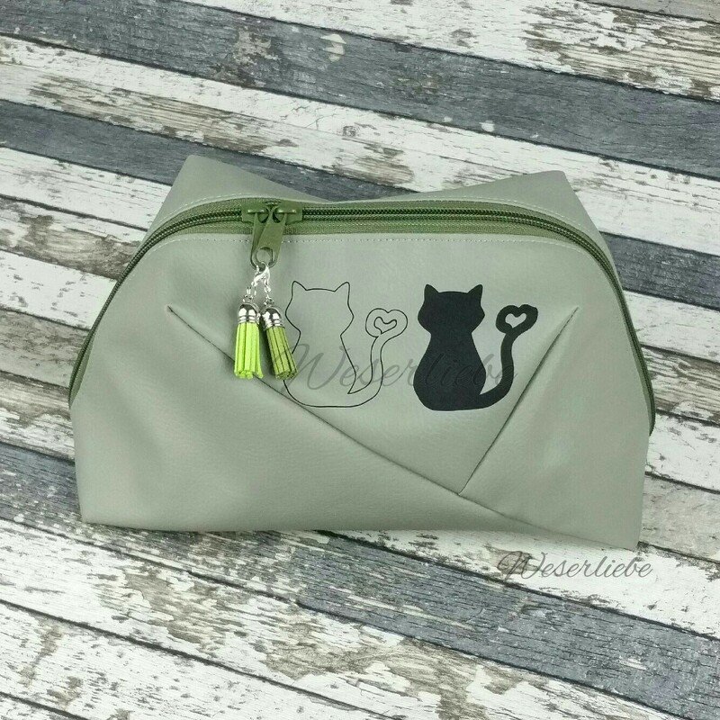Kosmetiktasche mit zwei unterschiedlichen Katzenplots (eine Kontur, eine schwarze Fläche) und grünen Quasten am Reißverschluss
