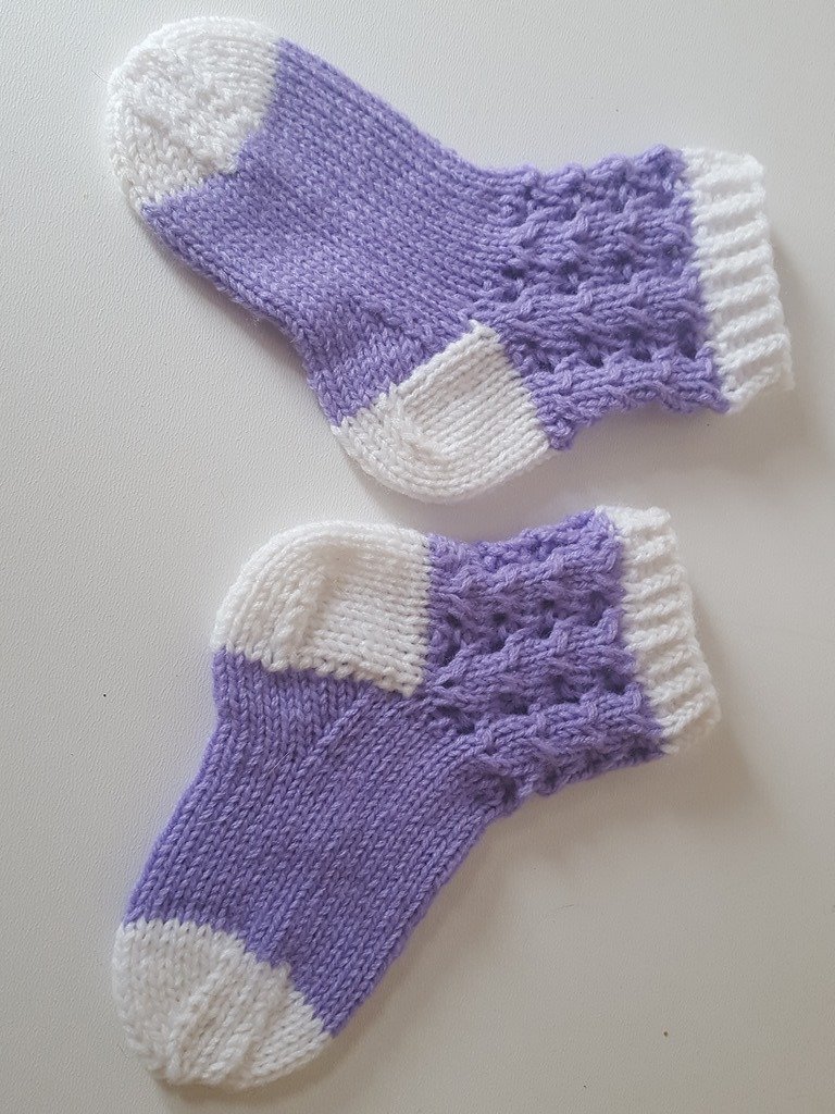 Paar gestrickter Babysocken in Flieder und Weiß mit Lochmuster am Schaft