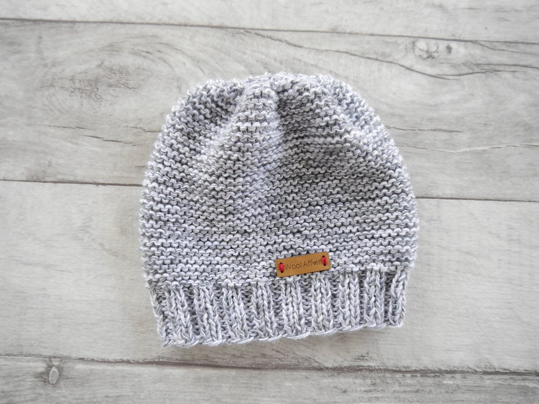 Grau-melierte Babymütze mit geripptem Bündchen auf hellem Holzhintergrund
