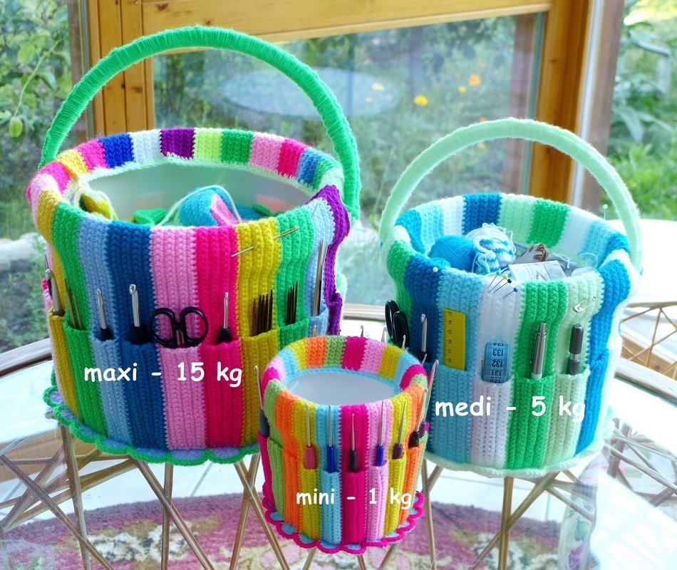 Three striped crochet-covered baskets in three sizes with exterior pockets holding crochet hooks and scissors on a table