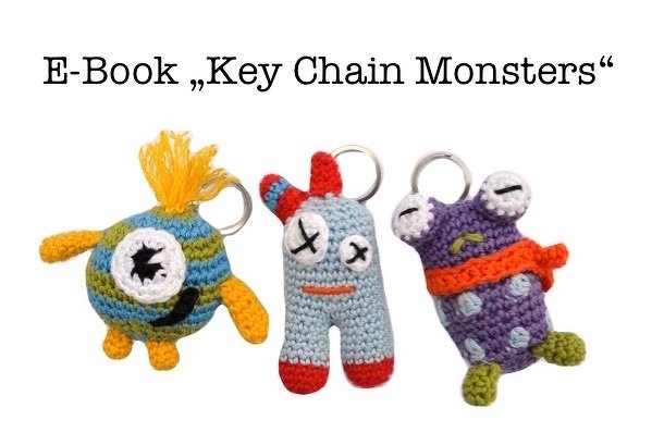 Three crocheted monster keychains in blue, gray, and purple with metal split rings; text above reads E-Book "Key Chain Monsters".