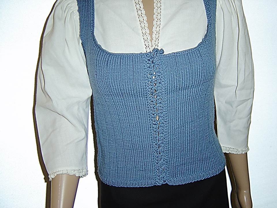 Hellblaues gestricktes Mieder mit quadratischem Ausschnitt und Zierschnürung vorne auf einer Schaufensterpuppe über einer weißen Spitzenbluse.