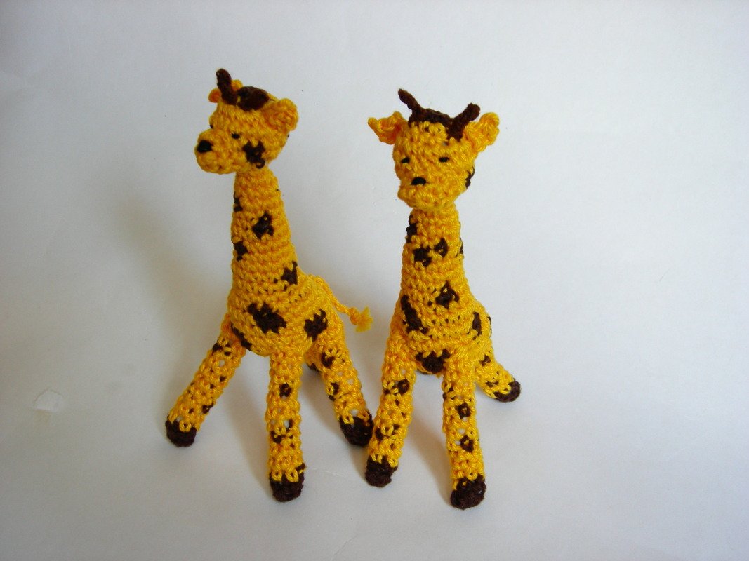 Zwei gehäkelte gelbe Amigurumi‑Giraffen mit braunen Flecken auf weißem Hintergrund