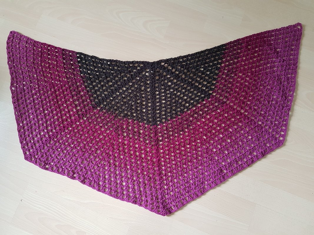 Gehäkeltes Dreieckstuch in Anthrazit und Magenta mit offenem Lochmuster auf hellem Boden
