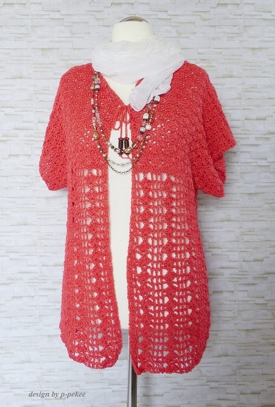 Korallfarbene Häkeljacke mit offenem Lochmuster und kurzen Ärmeln auf einem Mannequin