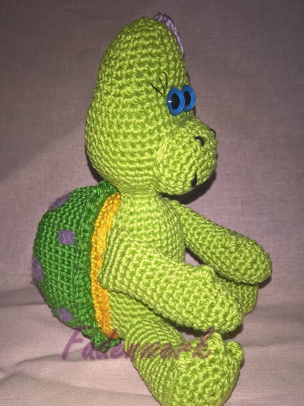 Seitenaufnahme einer gehäkelten grünen Schildkröte mit gepunktetem Panzer