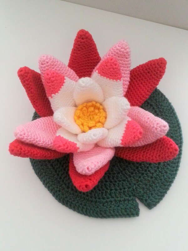 Gehäkelte Seerose mit mehreren Blütenlagen auf grünem Lotosblatt