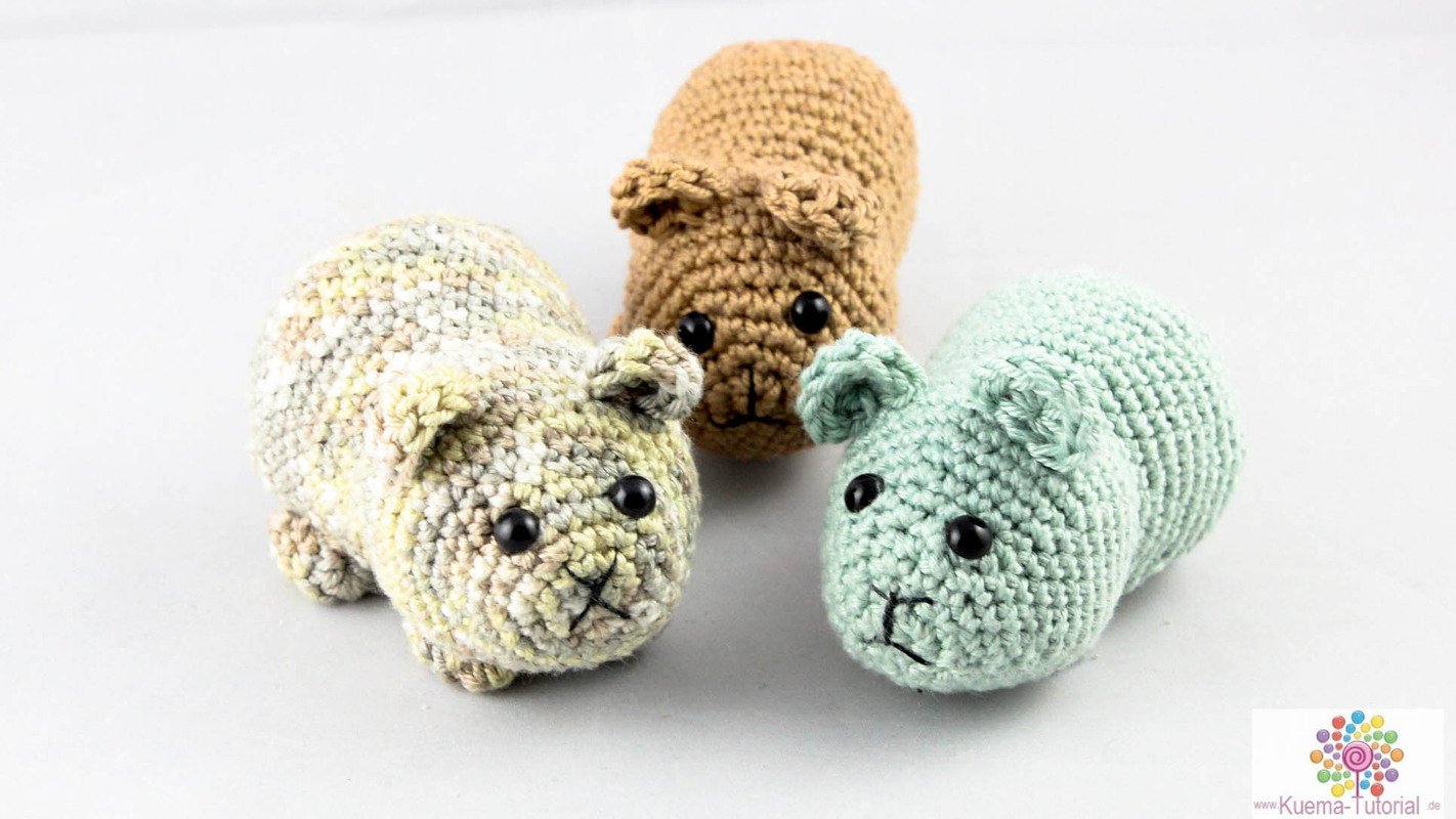 Drei gehäkelte Amigurumi-Meerschweinchen in beige, braun und mint auf hellem Hintergrund.