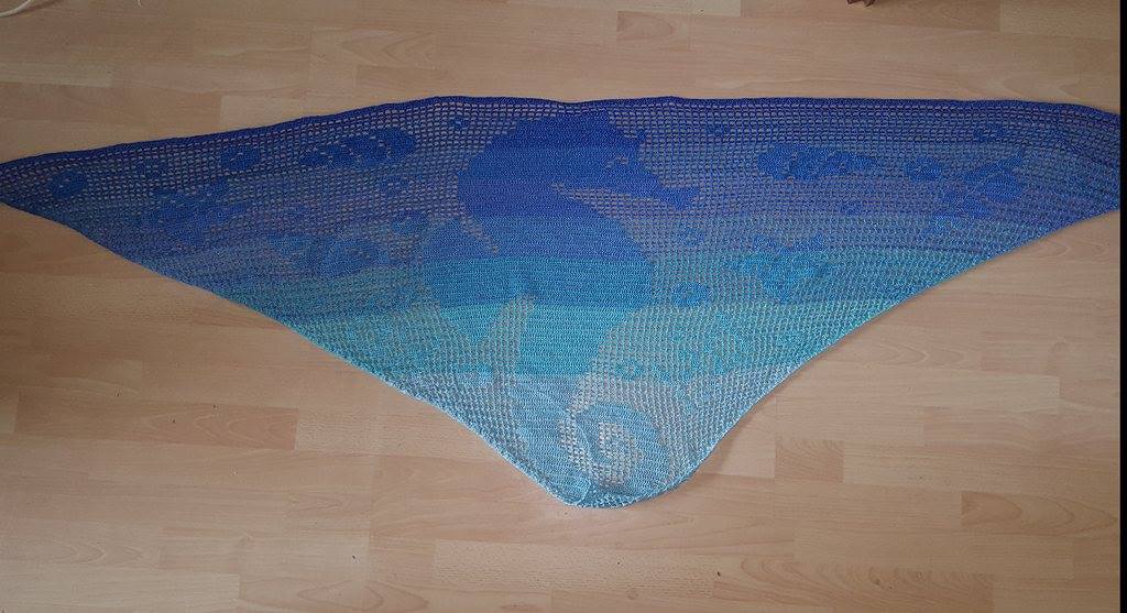 Gehäkeltes dreieckiges Tuch in Blau‑Türkis mit Seepferdchen‑Motiv auf Holzfußboden