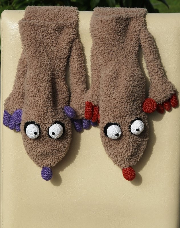 Zwei flauschige Handpuppen aus Flauschstoff mit weißen Häkelaugen und roten sowie violetten Pfoten