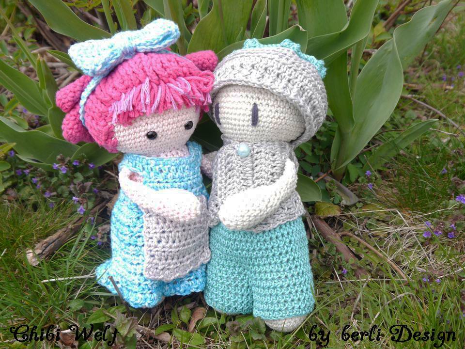 Zwei gehäkelte Amigurumi-Puppen (rosa Mädchen, türkis Junge) stehen im Gras