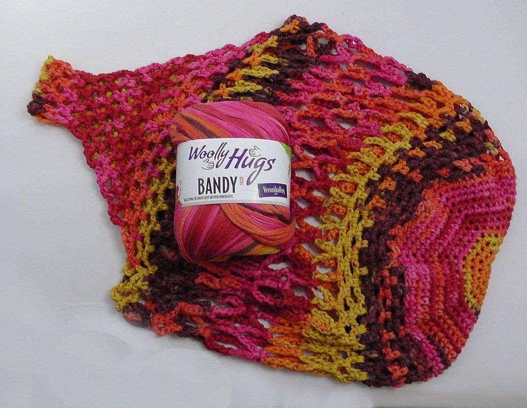 Gehäkelte Henkeltasche aus mehrfarbigem Garn mit Netzmuster und einem Knäuel Garn darauf