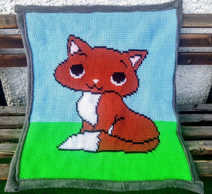 Handgehäkelte Babydecke mit sitzendem Fuchs auf blau-grünem Grund