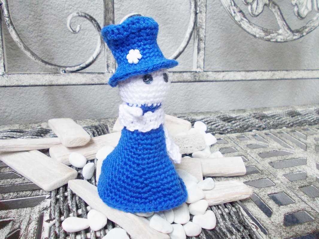 Amigurumi-Puppe in Blau mit Hut und weißer Blüte