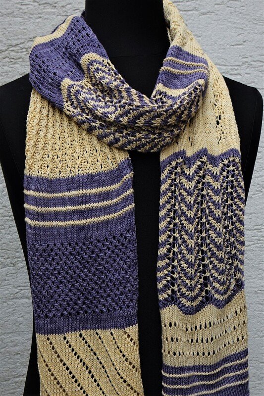 Zweifarbiger gestrickter Schal in Beige und Violett mit verschiedenen Loch- und Zickzackmustern auf schwarzer Schneiderpuppe.