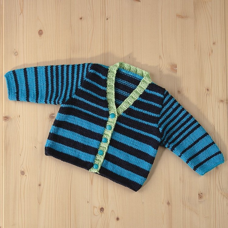 Gestrickte Babyjacke in Türkis und Dunkelblau mit hellgrüner Blende und Knopfleiste, auf hellem Holzuntergrund