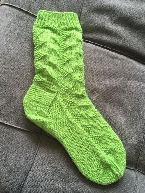 Leuchtend grüne handgestrickte Damensocke mit Chevronmuster auf Stoff