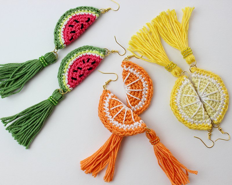 Three pairs of crocheted fruit slice earrings with matching tassels: watermelon, orange, and lemon, arranged on a white background.
