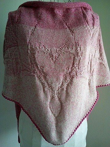 Pink knitted triangle shawl draped on a mannequin showing a central heart lace motif and narrow contrasting edge