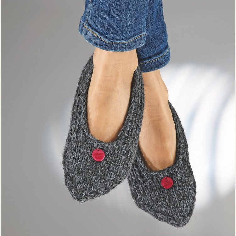 Nahaufnahme dunkelgrauer gestrickter Ballerinas mit rotem Knopf an Damenfüßen