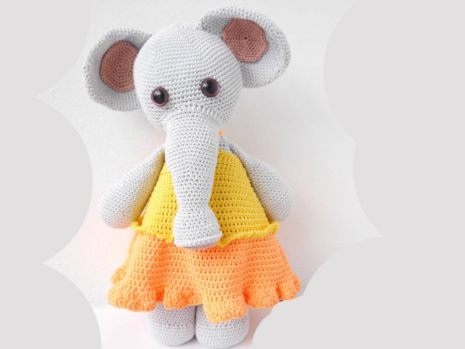 Gehäkelter Amigurumi-Elefant in Hellgrau mit gelbem Oberteil und orangem Rock