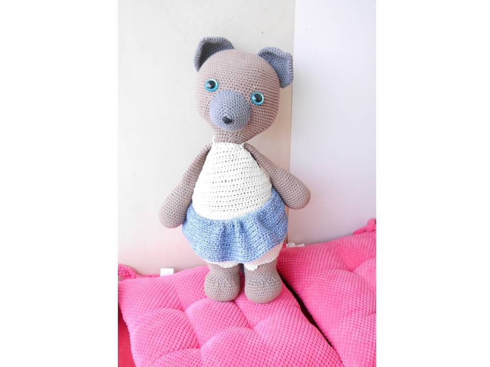 Gehäkelter Amigurumi-Bär in Grau mit weißem Oberteil und blau-weißem Rock, Blick auf Form und Maschen