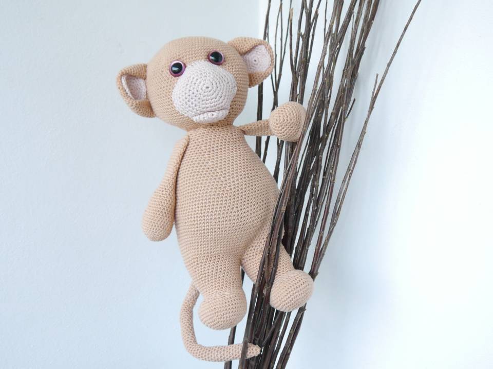 Nahaufnahme eines beigen gehäkelten Amigurumi-Äffchens mit erkennbaren Kopf-, Körper- und Gliedmaßenformen