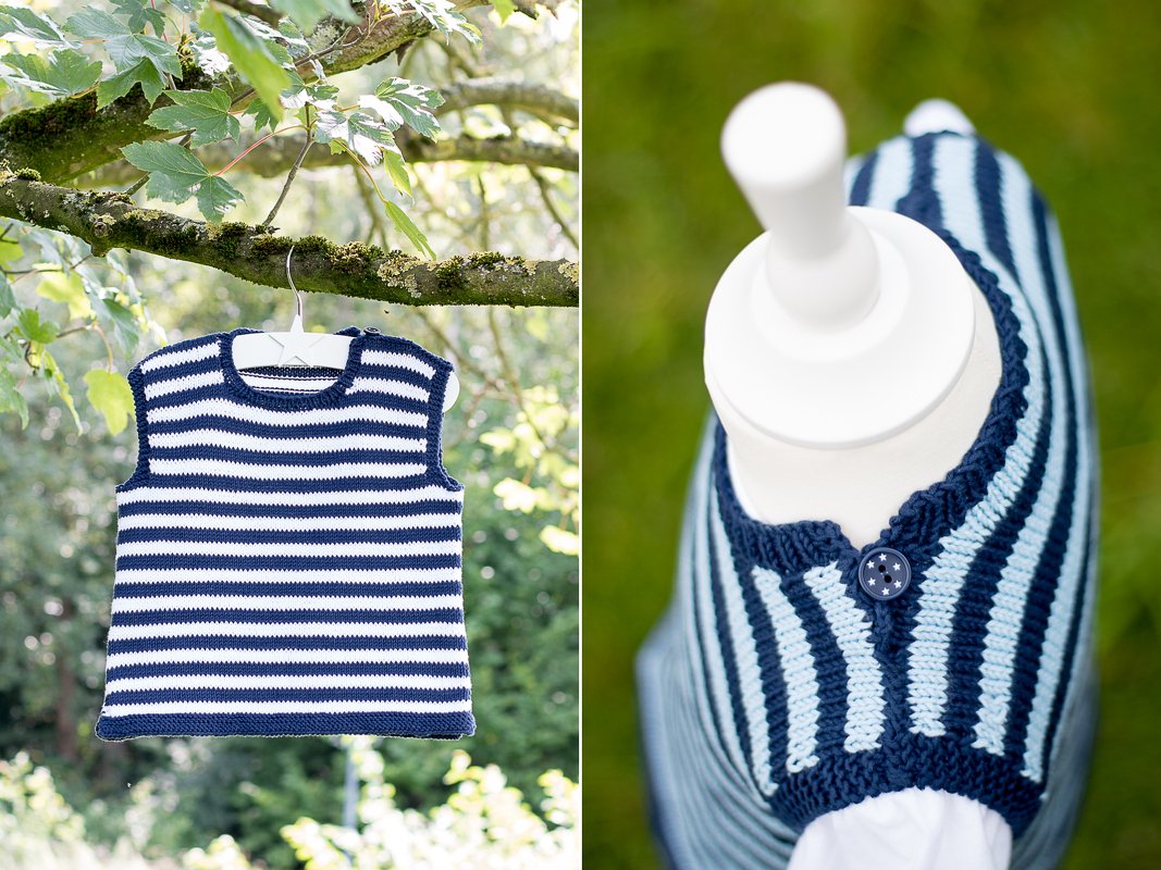 Ärmellose gestrickte Babyweste blau-weiß gestreift an einem Ast; Nahaufnahme zeigt hell- und dunkelblaue Streifen und einen Sternknopf.