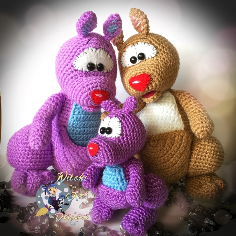 Drei gehäkelte Amigurumi-Tiere in Lila und Braun mit blauen Bäuchen, großen Augen und roten Nasen