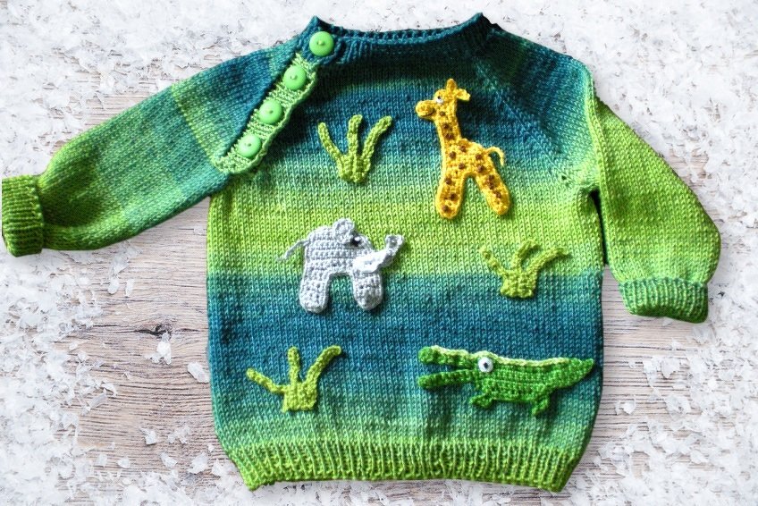 Handgestrickter Baby- und Kinderpullover in Grün- und Blautönen mit Giraffen-, Elefanten- und Krokodil-Applikationen und grünen Schulterknöpfen