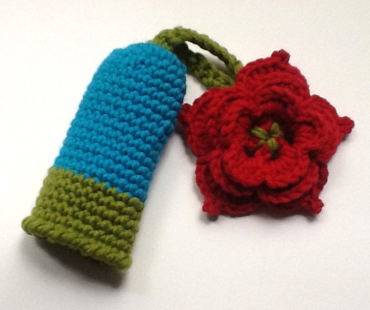 Gehäkelte Hülle in Türkis-Grün mit roter Häkelblume